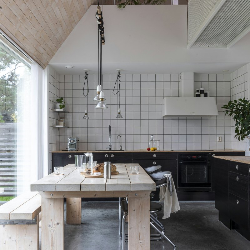 Skandinavisk kjøkken med langbord i lyst tre ved vinduet, dekket til frokost.