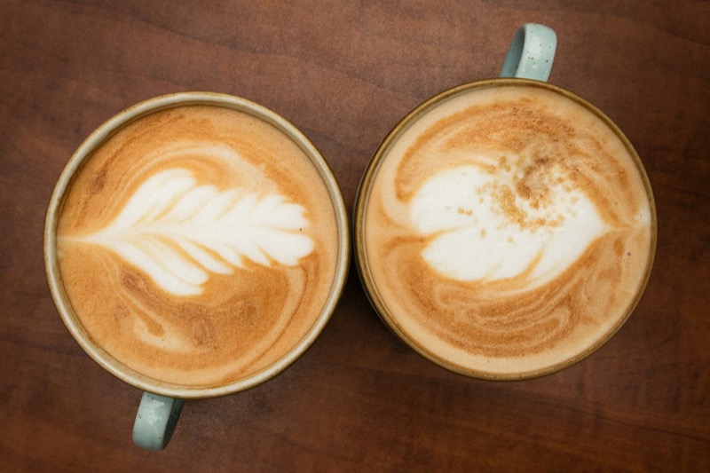 To like kaffekopper side om side på et mørkt trebord, sett ovenfra.
